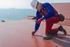 The image shows a worker testing the efficacy of Hempel marine coatings