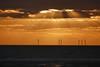 The image shows a generic image of offshore wind turbines at sunset