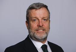 The image shows a headshot of Finlay Carson MSP in a black suit and tie