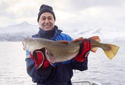 Chef Michel Roux holding a fish and looking mightily pleased