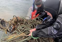 Divers hauling in ghost gear on to a vessel