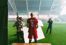 Erling Haaland with his back to the camera at a football stadium being filmed for an ad campaign by the Norwegian Seafood Council