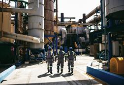 Three workers outside at a fish oil and fishmeal factory