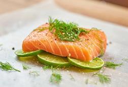 Piece of salmon on slices of lime with fennel fronds