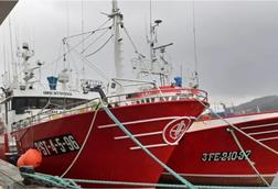 Two red and white fishing vessels at port