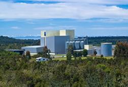 Image of BioMar's feed production factory in Ercilla, Chile with trees in the foreground, mountains in the back on a sunny day