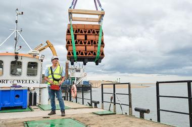 The image shows one of the clay bricks designed to house juvenile oysters being lowered into the water