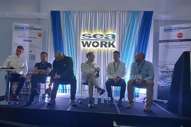 The image shows the speakers seated on stage