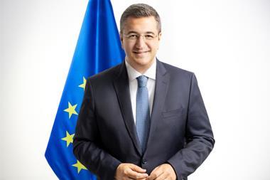 The image is of Commissioner Tzitzikostas standing in front of the EU flag