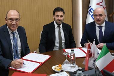 The image shows parties from the three companies signing the MoU