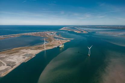 Aerial shot of Thyborøn Port in Denmark two wind turbines and a service vessel at dock