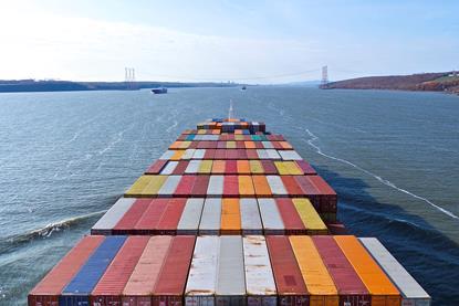 Image shows the view from the front of a container ship at sea with the deck full of cargo