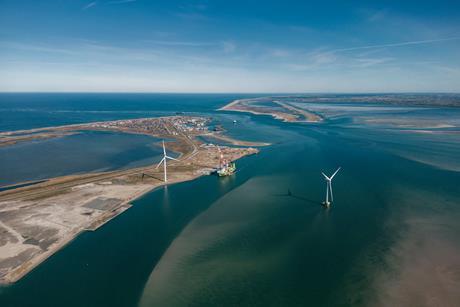 Aerial shot of Thyborøn Port in Denmark two wind turbines and a service vessel at dock