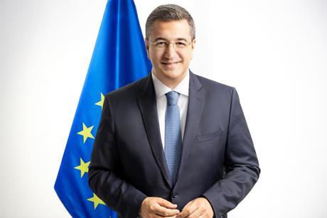 The image is of Commissioner Tzitzikostas standing in front of the EU flag