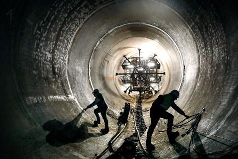 Silhouetted workers inside a tunnel within the Tâmega River Hydroelectric Dam
